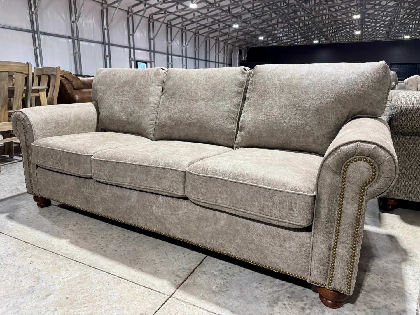 A three-seat sofa featuring beige, distressed upholstery that resembles faux leather